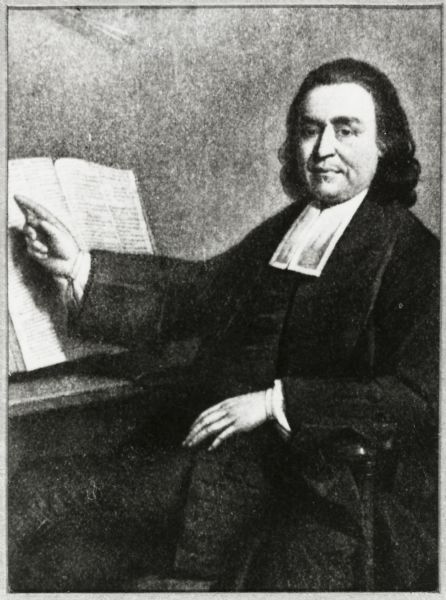 Portrait of Mohegan minister and preacher Samson Occom, posed sitting with his finger on a Bible on a bookstand, with Indian implements visible on the wall.