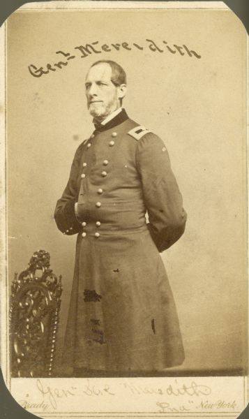 Three-quarter length studio portrait of General Meredith standing near a chair with his hand inside his jacket.