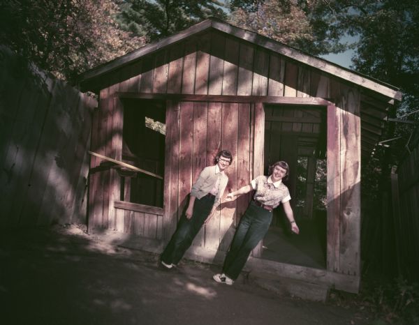 Two young women appearing to defy gravity outside a shack at the Wonder Spot.