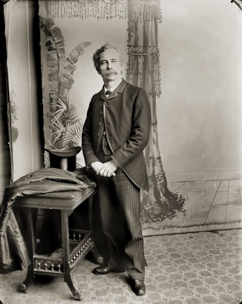 Studio portrait in front of a painted backdrop of formally-dressed Henry Hamilton Bennett. This is his wedding portrait, which was made when he married Evaline Marshall.