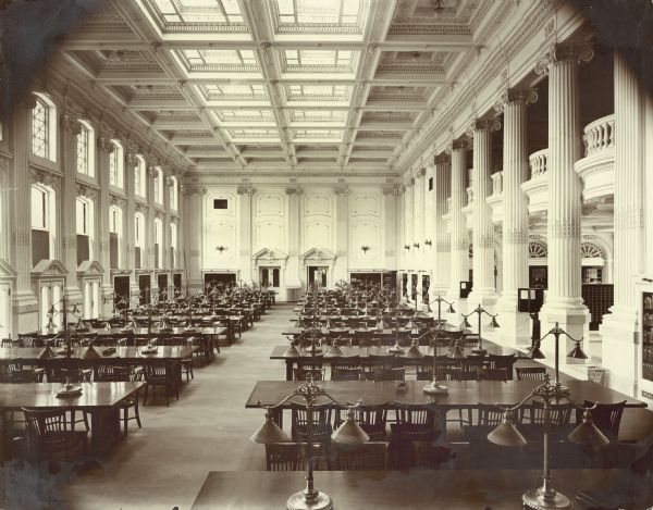 Elevated view of the length of the Historical Society Library Reading Room, including tables, chairs, lamps and skylight.