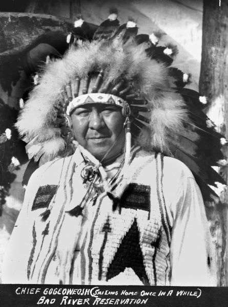 Bad River Ojibwe Chief Gogeoweosh (<i>Sailing Home Once in a While</i>). Chief Gogeoweosh is wearing a woven vest over a shirt and a bead and feather war bonnet.