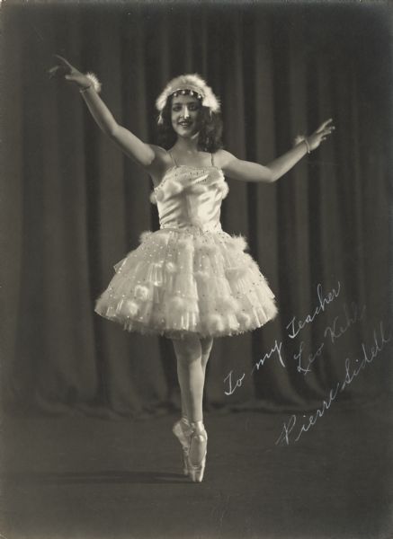 Pierre Sidell poses in a ballet dancing costume and pointe shoes, standing en pointe. The photograph is inscribed, "To my Teacher Leo Kehl. Pierre Sidell".