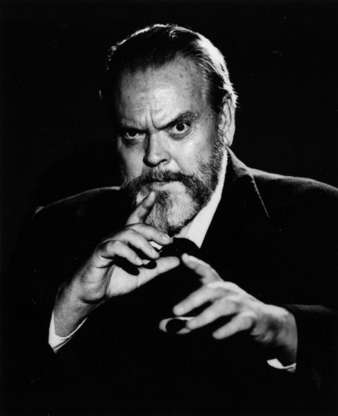 A classic Orson Welles publicity still showing him looking intensely into the camera while gesturing with his hands.