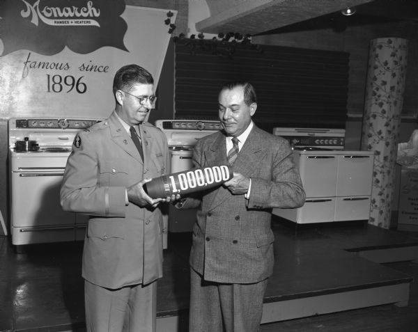 Col. Robert K. Haskell (left) receiving the one millionth shell manufactured by the Malleable Iron Range Co. of Beaver Dam in a ceremony at the manufacturing plant. H.T. Burrow (right), President of the company, presented the shell during a ceremony. Three Monarch ranges can be seen in the background.