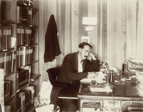 Charles McCarthy writing at his desk in his office.