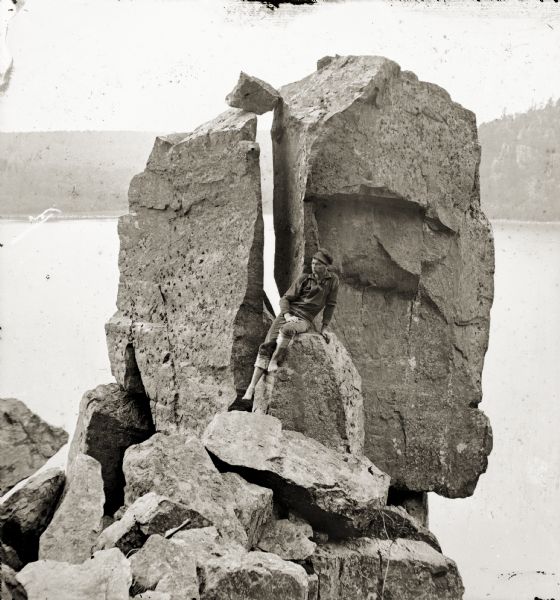Devil's Lake vicinity; a young man is sitting on rocks in front of Cleft Rock on East Bluff.