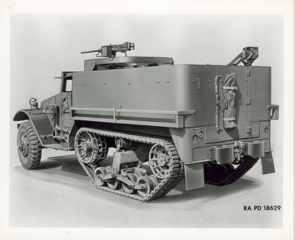 Truck with Gun Mount Three-quarter view illustration from rear of the left side of a truck, with a gun mount on top of the cab. A shovel and pick are mounted on the side of the truck below the driver's side door. A bag is strapped to the back of the truck, which has a set of crawler tractor wheels. This truck was likely a M9 half truck military vehicle produced by International Harvester for the United States military.