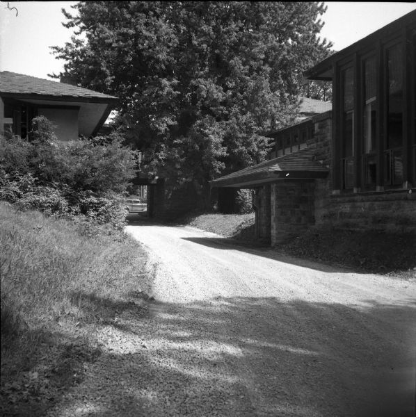 Exterior view from driveway of the entry to the Hillside Playhouse, with a large tree obscuring part of the building in the background.