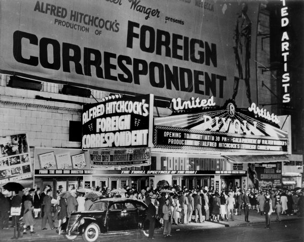 View from street of the Rivoli Theater in Times Square. There is a large crowd on the sidewalk outside the theater. The marquee says the premiere of the film "Foreign Correspondent" is tonight.