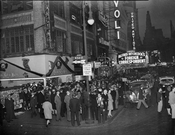 Slightly elevated view from street corner at Broadway and West 50th Street of the Rivoli Theater in Times Square when it was screening the movie "Foreign Correspondent." A large crowd is on the sidewalk outside of the theater.