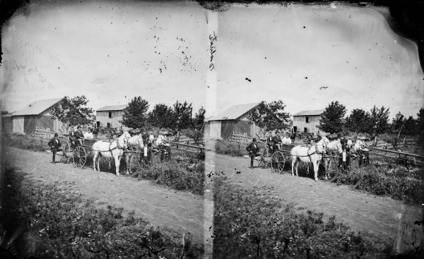 This image is one of many taken by Dane County photographer Andreas Larsen Dahl. Many of them depict family posed in front of their homes wearing their best clothes and displaying some of their special possessions. This portrait of an unidentified family suggests that their matched team of white horses and the farm were the possessions of which they were most proud. Behind them is a barnyard with a barn and another large outbuilding.