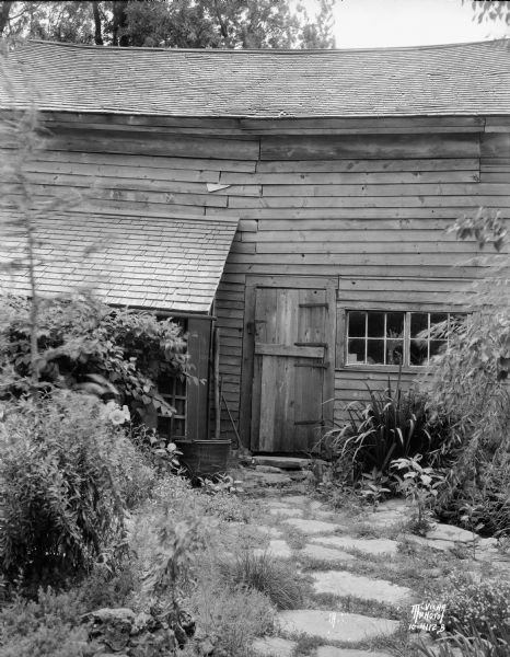 Barn at "The House Next Door" View along stone path leading to the side door of barn/carriage house at Ralph Warner's "The House Next Door," aka the Lovejoy-Duncan House, 11219 N. Webster Street.