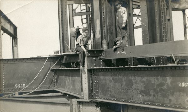 Riveting Gang on Capitol Dome Three men posing while doing rivet work on the Wisconsin State Capitol dome. All three men have been numbered, in correspondence with the caption.
Caption on back of image reads: Riveting gang at work on the 82' level of dome proper.
1 - Red McCabe
2 - Alex Doyle
3 - Able Hermansen