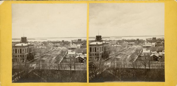 Elevated view up Wisconsin Avenue showing City Hall on the corner at Mifflin Street on the left, with the Post Office to the right. Further down is the Presbyterian Church. Lake Mendota is in the distance.