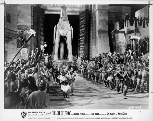 "Helen of Troy" Film Still A large group of men are pulling the wooden Trojan horse through a large gate, and into the city of Troy, as people cheer in a scene from the film Helen of Troy.