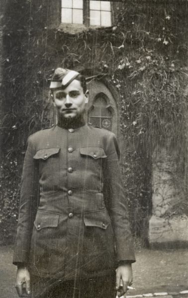 John Lavalle A candid portrait of John Lavalle in uniform standing in front of a vine-covered building. He is holding a cigarette in his left hand.