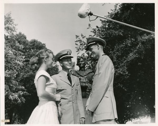 "Men of Annapolis" Actors Actress Joan Dupuis and actors Bob Arthur and Carlton Carpenter stand in front of the statue of Tecumseh at the U.S. Naval Academy. A microphone boom is extended above their heads. Arthur and Carpenter are dressed in Navy uniforms. The three were cast members of the television show "Men of Annapolis."