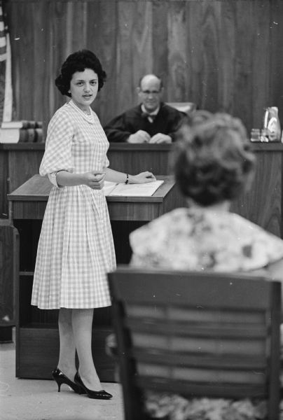 Shirley Schlanger Abrahamson in Court Shirley Abrahamson standing in a courtroom. A judge is sitting behind her. She is addressing a woman sitting in the foreground.