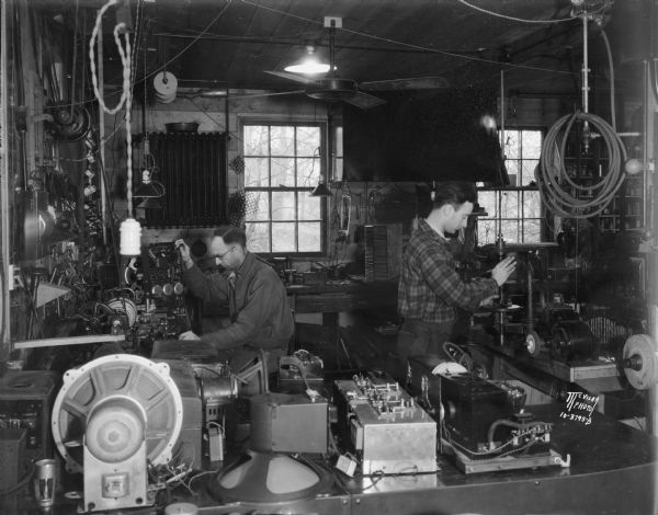 Left interior of Kidder Radio Shop, 113 N. Baldwin Street. Shows two men working on radios.
