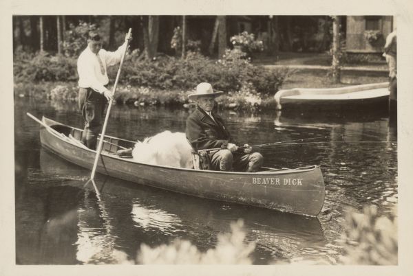 President Calvin Coolidge fishing at Cedar Island Lodge, rustic lodge of Henry C. Pierce, 35 miles from Superior, Wisconsin, on the Brule River. This lodge was later dubbed The Summer White House. The canoe is named Beaver Dick and the guide is John LaRock. There is a large, white dog in the canoe behind Coolidge.
