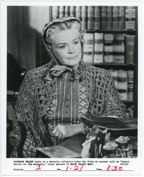 Rosemary DeCamp in <i>Death Valley Days</i> Rosemary DeCamp plays a widow named Canary Harris in an episode of the TV show <i>Death Valley Days</i>. She appears to be sitting at a desk in a lawyer's office. DeCamp is wearing a bonnet and has a shawl over her shoulders.