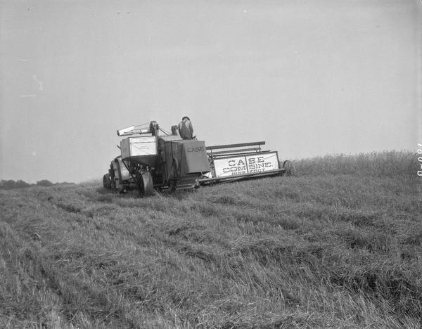 Man cutting and threshing with Case 9-foot combine, at the University of Wisconsin Hill Farm.