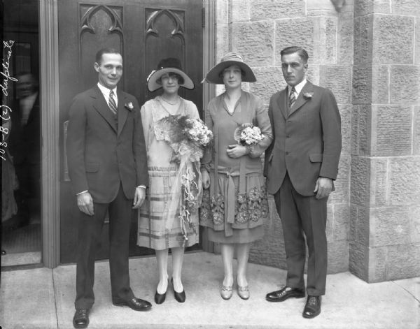 Mildred House and Lloyd Coleman wedding party, with the bride and groom with the maid of honor and best man standing outdoors in front of the church doors.
