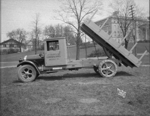 "White" dump truck with raised bed. The sign painted on the side of the driver's side door reads: "J. P. Cullen & Son, Contractors."