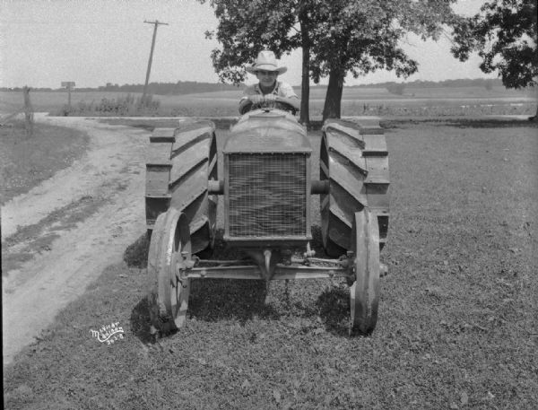 View from front towards a man sitting on a Fordson tractor, which has extra rims.