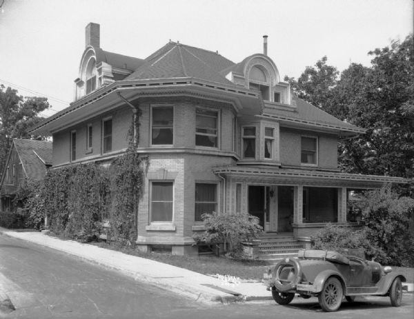 View from street towards the Alpha Omega Pi House, with a convertible automobile parked in front of house at 626 North Henry Street.