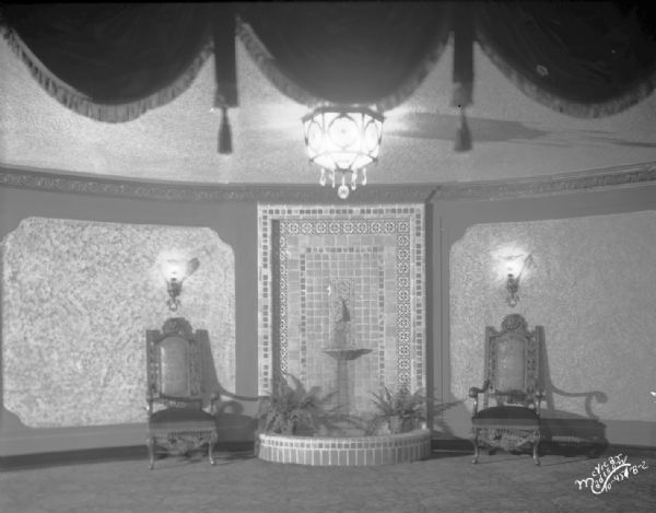 Lobby of the Capitol Theatre, featuring a tiled fountain with ornate chairs on either side.