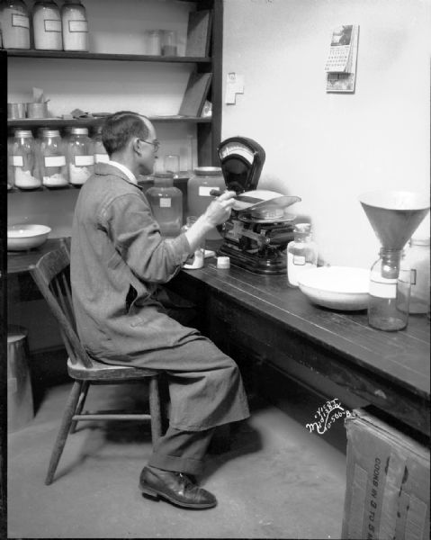 Man measuring chemical CaCO4 on Toledo Scale in Ricketts laboratory at Agriculture Chemistry Building, University of Wisconsin.