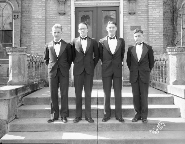 Four fraternity brothers in front of Alpha Kappa Lambda fraternity house, 28 East Gilman Street. The building is known as the Keenan House, and was built in 1857.