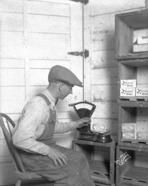 Man weighing butter on Toledo scale at Evans Creamery, Mt. Horeb.