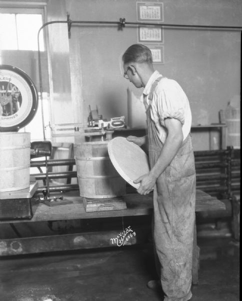 Man weighing bucket on old bench scale at Federation Creamery.