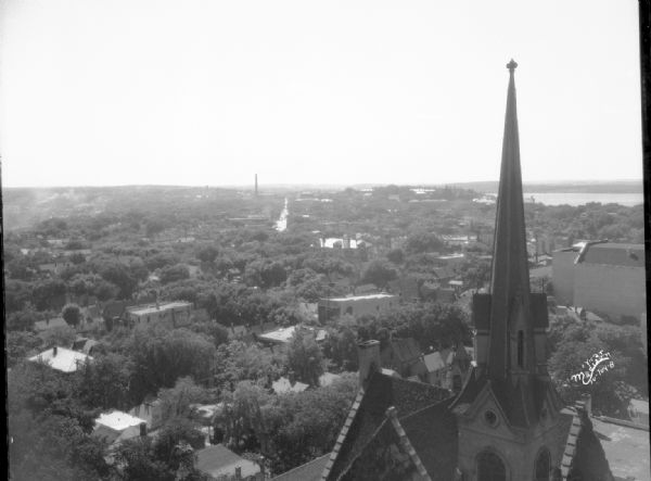 Elevated view of near west side from the Loraine Hotel, showing the steeple of the First Congregational Church at 202 W. Washington Avenue in the foreground. Lake Mendota is in the far background.