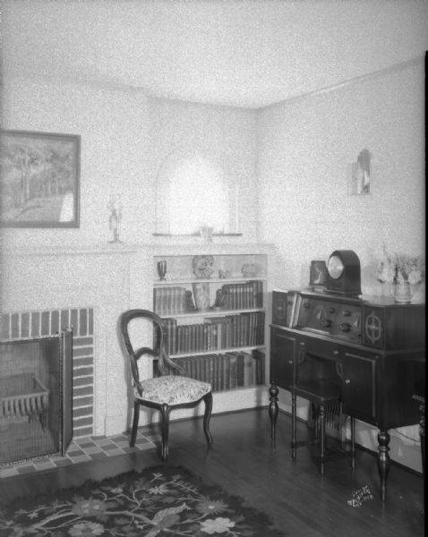 Albert Hinman Residence, 1 Vista Road, showing the living room interior with fireplace and bookcase detail. There is a floor model radio on the right.