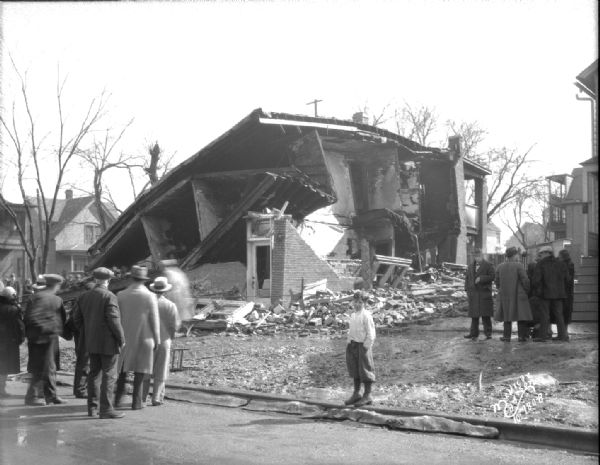 Exploded store of Natalie Troia, 102 S. Park Street from Milton Street, with people looking on. Corner of Park and Milton Streets.