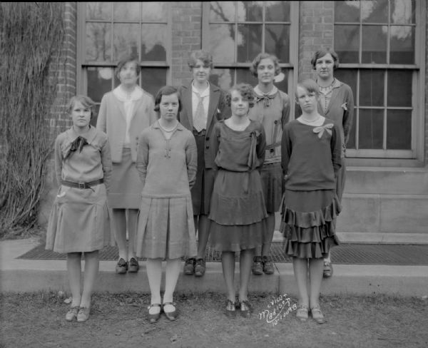 Outdoor group portrait of eight girls of Central High School who are athletic letter wearers.