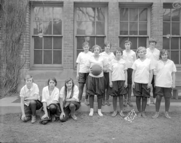Outdoor group portrait of the Central High School 9A girls basketball team. They are dressed in bloomers.