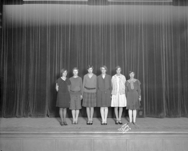 East High School reading contest, with six girl winners standing on a stage.