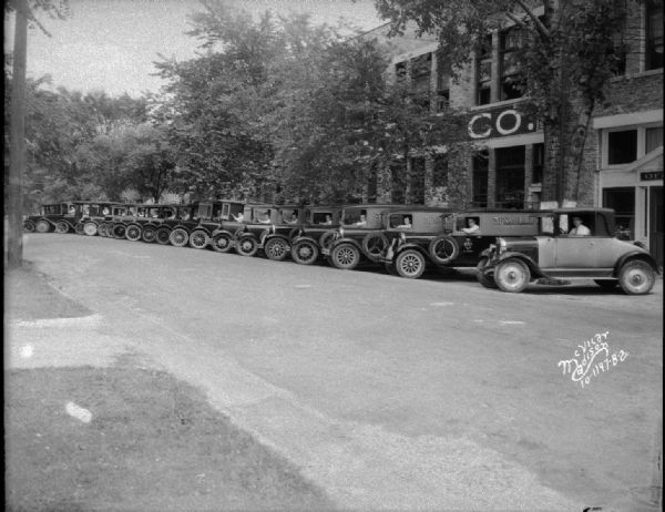 Fleet of 19 3-F Steam Laundry trucks and one automobile with drivers in the driver's seats at the steering wheel. They are parked in front of office and plant at 731-747 E. Dayton Street.