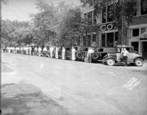 Fleet of 19 3-F Steam Laundry trucks and one automobile with drivers standing beside the vehicles in front of office and plant at 731-747 E. Dayton Street.