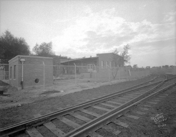 Carbide & Carbon Chemicals Co. Pyrofax plant under construction, 130 Fair Oaks Avenue, looking towards a chain link fence and gate surrounding the plant. Railroad tracks are in the foreground.
