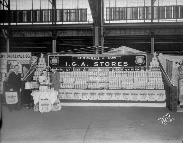 Gfroerer & Son's Independent Grocer's Alliance of America. (I.G.A.) grocery store booth at East Side Business Men's Association (ESBMA) Fall Festival. There are two male customers, and one woman is pouring Silver Buckle coffee.