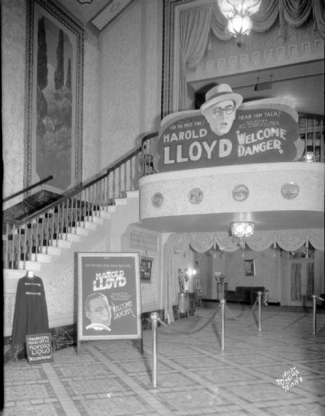 Capitol Theatre lobby with a Harold Lloyd sign. Text on poster reads: "Harold Lloyd," "Welcome Danger," and "Hear him talk."