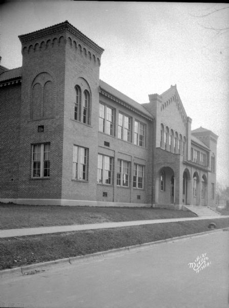 Three-quarter view from street towards the left corner of the building, with the roofed front entrance of Lowell Elementary School at 401 Maple Avenue.
