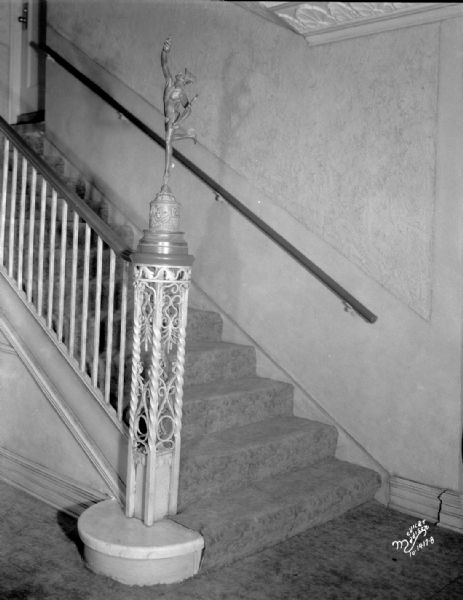 Verticle interior view of Eastwood Theatre featuring staircase and newel post with statue of Mercury.