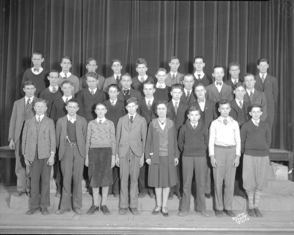 East High School Boys Glee Club. A woman is standing in the center of the front row.
